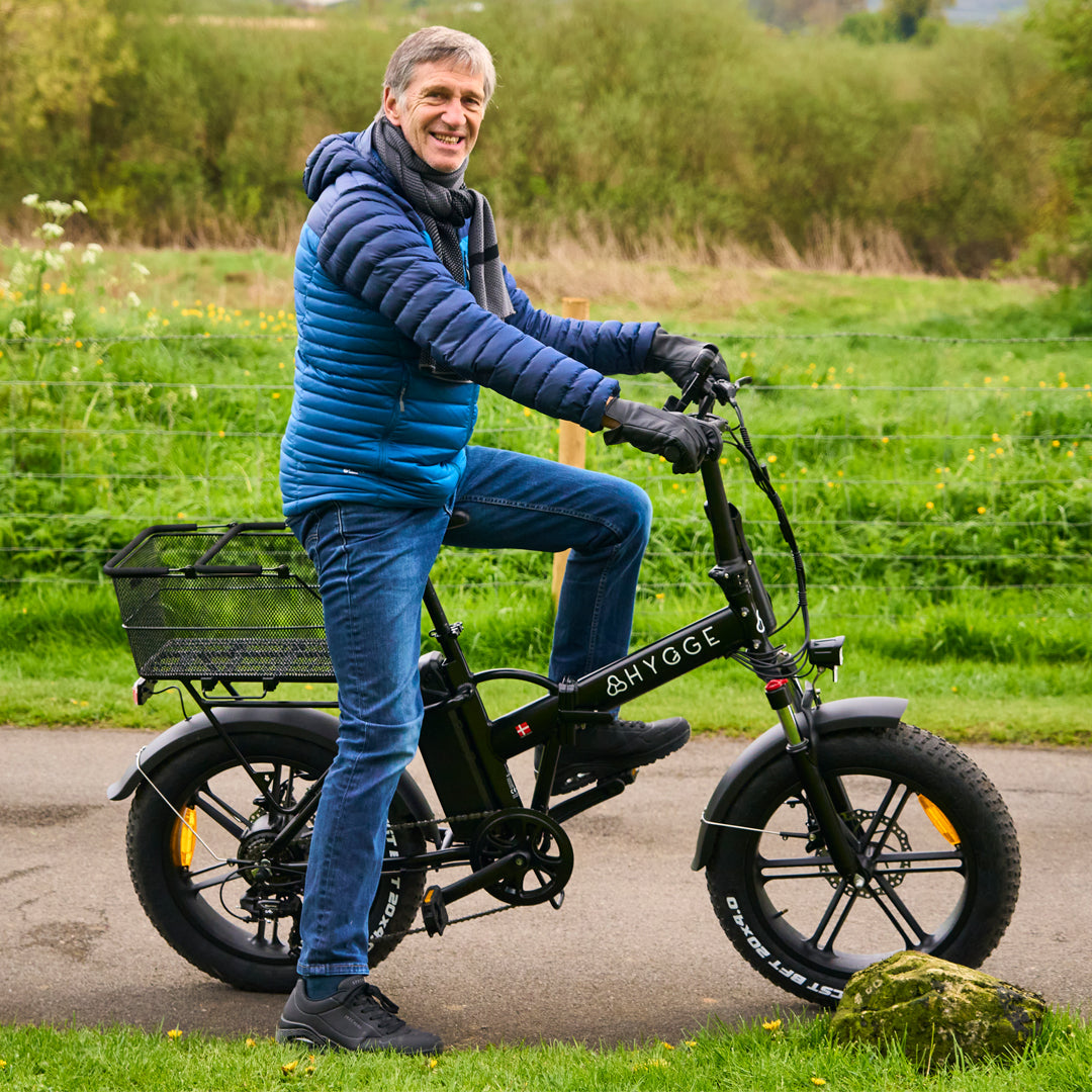 Smiling rider on a black Hygge folding fat tyre e-bike on a countryside path